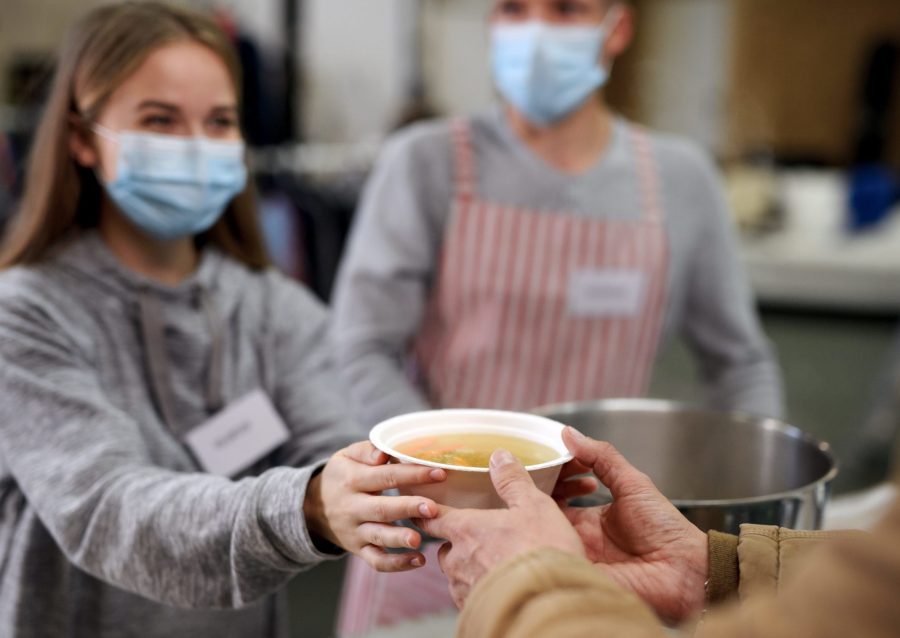 Volunteer handing out soup with a mask on.