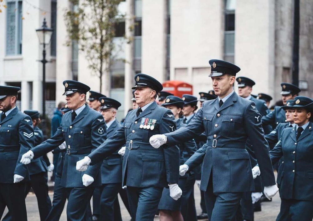 A group of people dressed in their military uniforms marching in the street