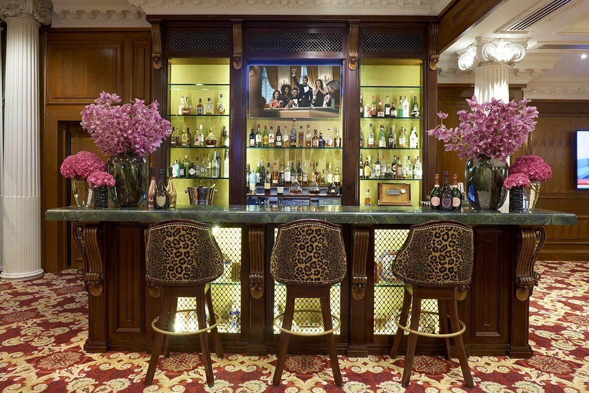 Three stools at a bar stocked with wine and spirits