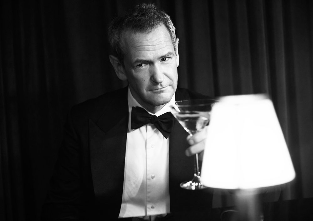 Alexander Armstrong holding a martini in a suit.