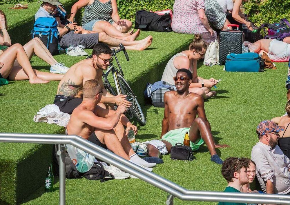 People sunbathing in London on astroturf.