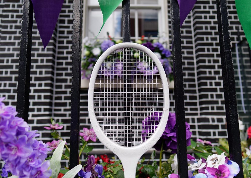 Image of a tennis racket in front of a black metal gate.