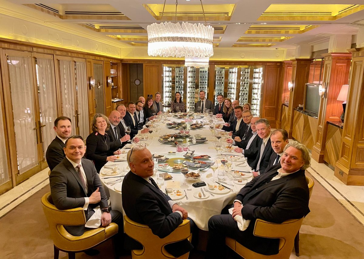 Casino bosses are around a large table in suits having a meal.